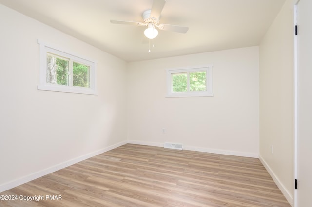 unfurnished room featuring light wood-style floors, plenty of natural light, visible vents, and baseboards