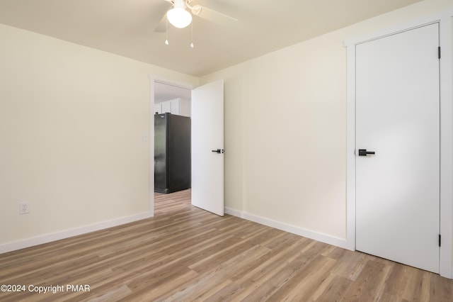 empty room featuring light wood-type flooring, baseboards, and a ceiling fan