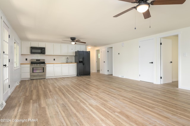 kitchen featuring light wood finished floors, decorative backsplash, black appliances, white cabinetry, and a sink