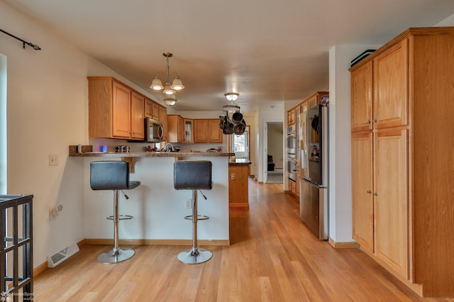 kitchen with glass insert cabinets, a peninsula, stainless steel appliances, and light wood-style flooring