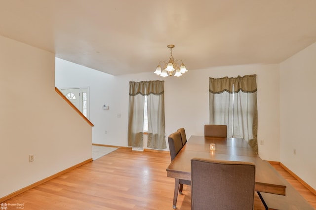 dining room featuring a chandelier, light wood-style flooring, and baseboards