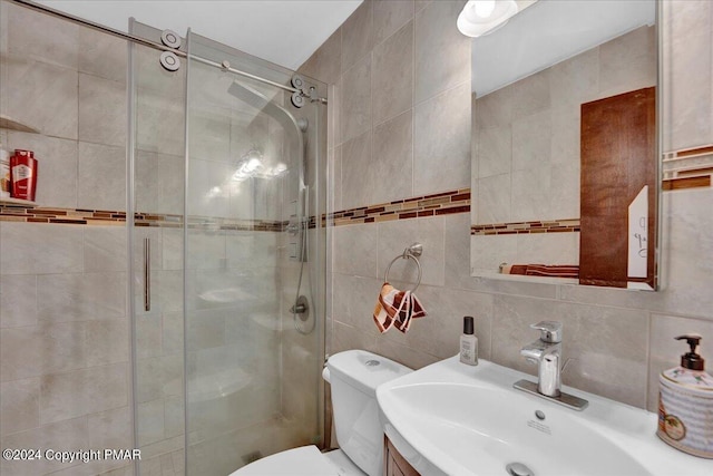 bathroom with backsplash, a shower stall, toilet, vanity, and tile walls