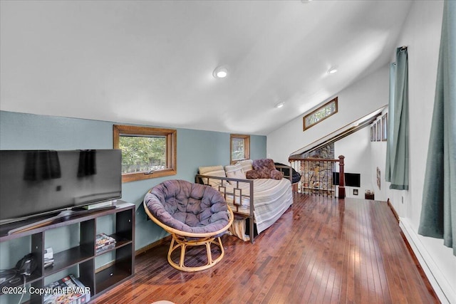 bedroom with a baseboard heating unit, lofted ceiling, and wood-type flooring