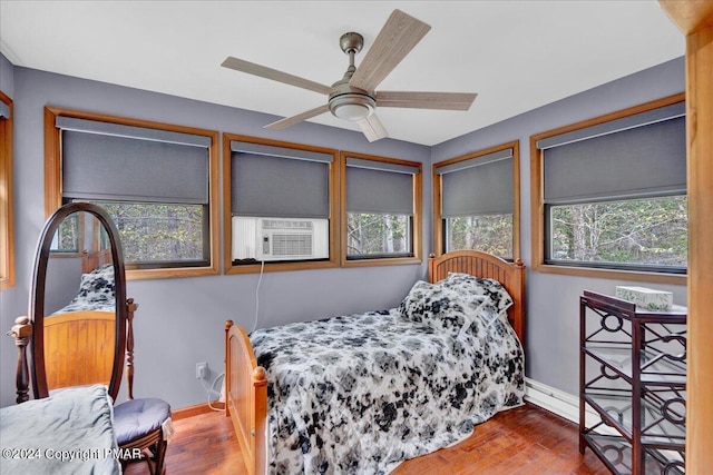 bedroom with a ceiling fan, cooling unit, wood finished floors, and baseboards