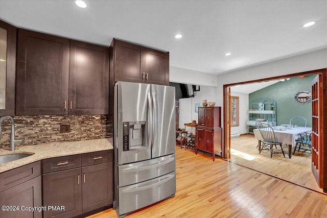 kitchen with light wood-style flooring, stainless steel refrigerator with ice dispenser, a sink, tasteful backsplash, and dark brown cabinets