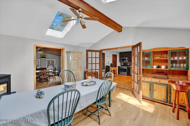 dining room with lofted ceiling with skylight, wood finished floors, and ceiling fan