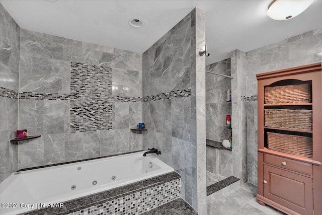 bathroom featuring tile walls, a tub with jets, and a tile shower