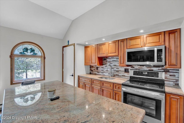 kitchen featuring a sink, lofted ceiling, light stone countertops, and stainless steel appliances