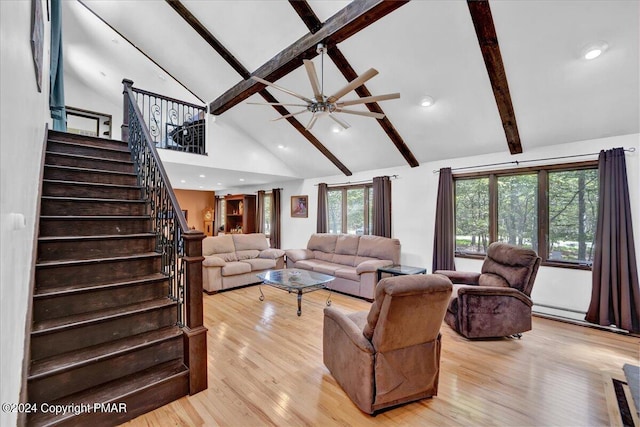 living area with beam ceiling, high vaulted ceiling, stairway, light wood finished floors, and baseboard heating