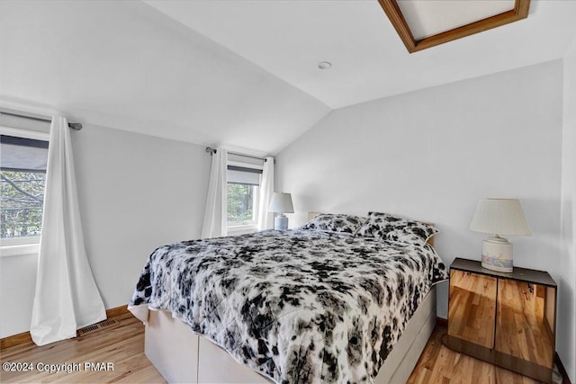 bedroom with light wood-type flooring, visible vents, and vaulted ceiling