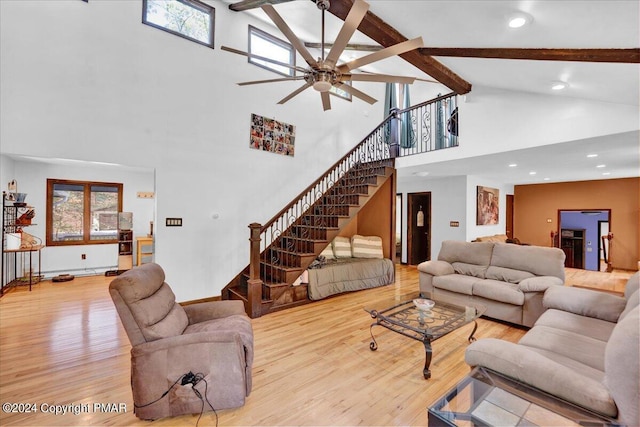 living area with beam ceiling, stairway, wood finished floors, and ceiling fan