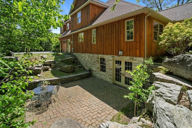 127 Timber Lake Dr, Canadensis, PA 18325 - view of side of property with a shingled roof, french doors, a patio area, board and batten siding, and stone siding