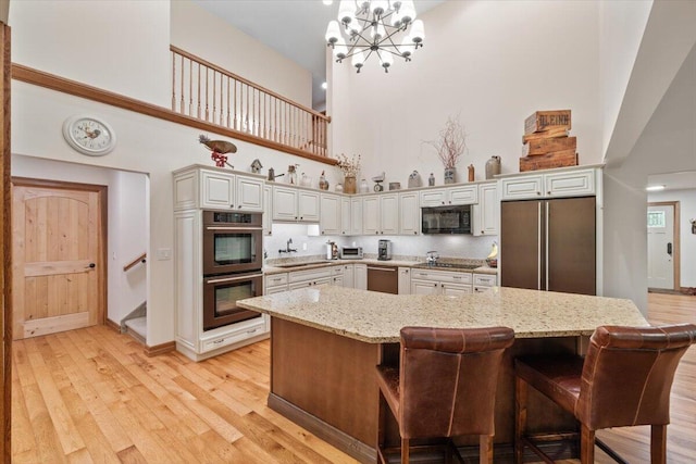 127 Timber Lake Dr, Canadensis, PA 18325 - kitchen with a high ceiling, black appliances, a sink, light wood-type flooring, and a chandelier