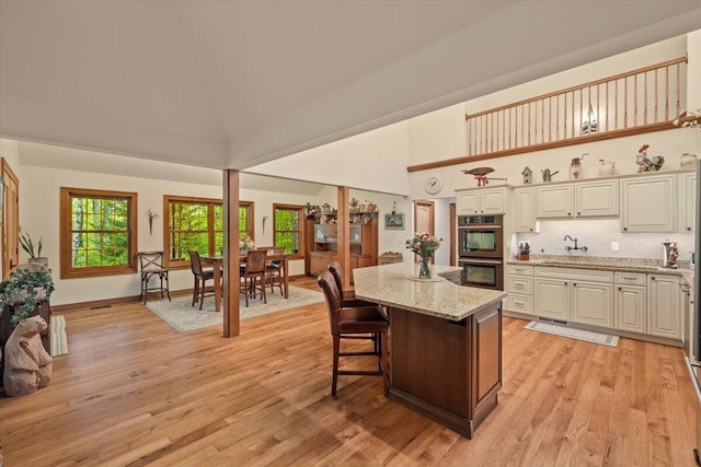 127 Timber Lake Dr, Canadensis, PA 18325 - kitchen with double wall oven, light wood-type flooring, a high ceiling, a center island, and light stone countertops
