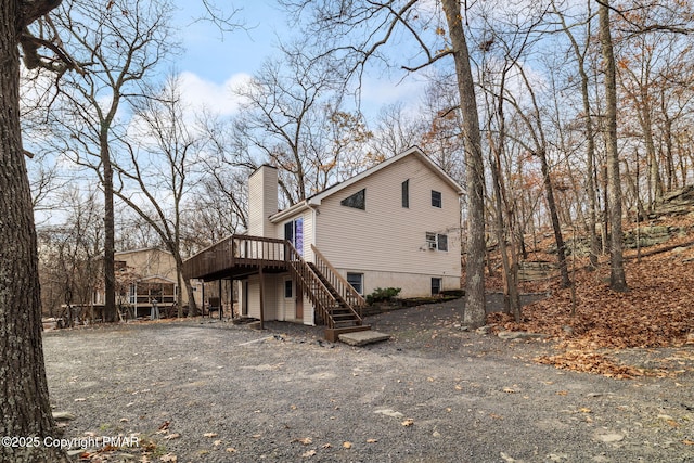 view of property exterior featuring stairs, a chimney, and a deck