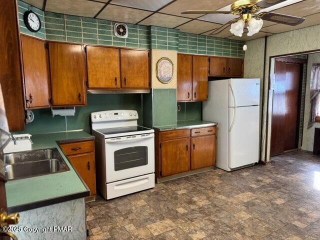 kitchen with ceiling fan, sink, white appliances, and a paneled ceiling