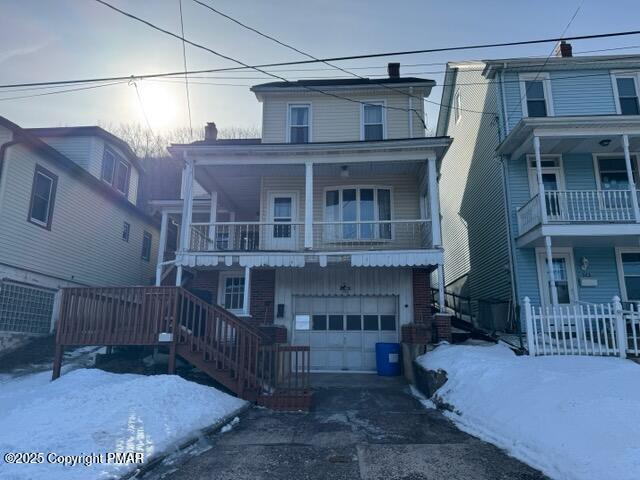 view of front of home with a balcony, an attached garage, driveway, and a chimney