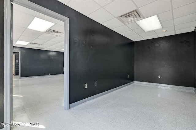 empty room featuring a paneled ceiling, visible vents, baseboards, and speckled floor