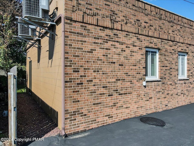 view of property exterior featuring brick siding, fence, and central air condition unit