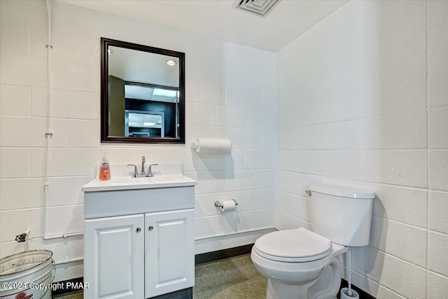 bathroom with toilet, visible vents, tile walls, and vanity