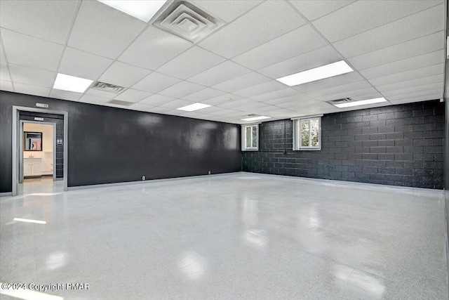 below grade area featuring visible vents, a paneled ceiling, and concrete block wall