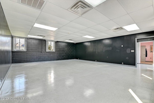 basement featuring concrete block wall, visible vents, and a paneled ceiling