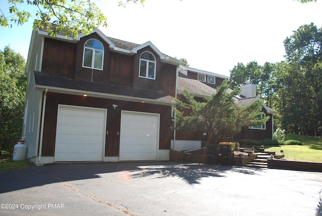 view of front of property featuring aphalt driveway, a garage, and a shingled roof