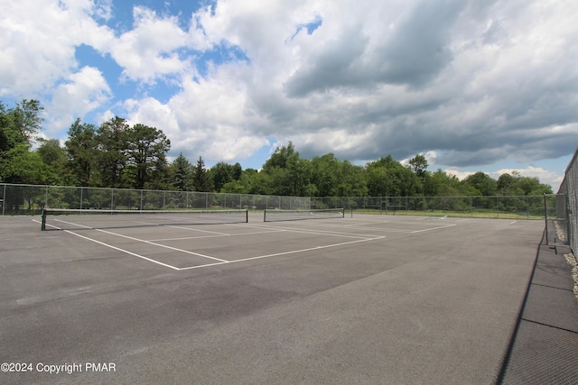 view of tennis court with community basketball court and fence