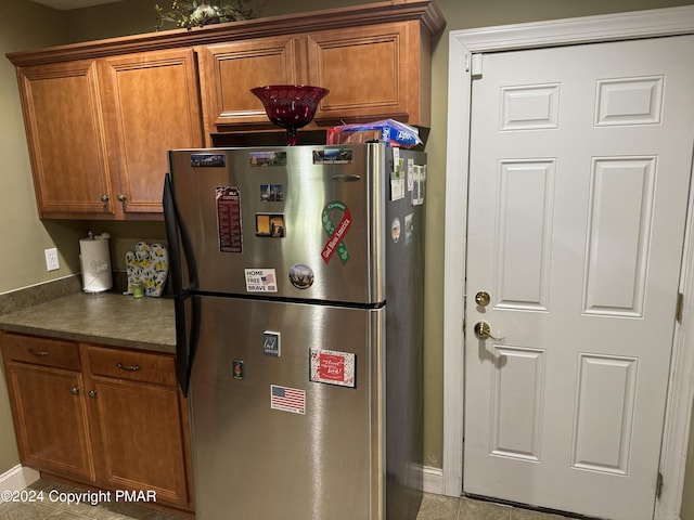 kitchen with dark countertops, brown cabinetry, and freestanding refrigerator