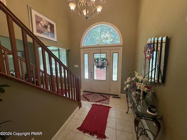 foyer with light tile patterned floors, stairway, an inviting chandelier, and a towering ceiling