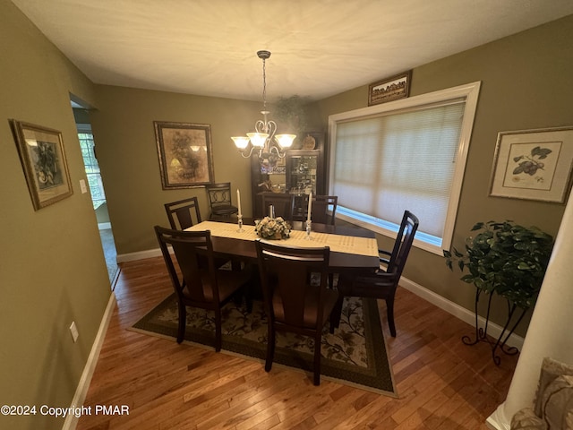 dining space featuring baseboards, a notable chandelier, and wood finished floors