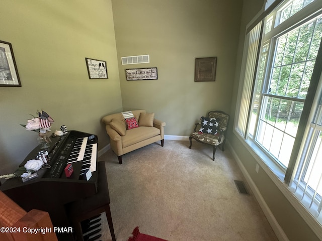 living area with baseboards, visible vents, and carpet floors