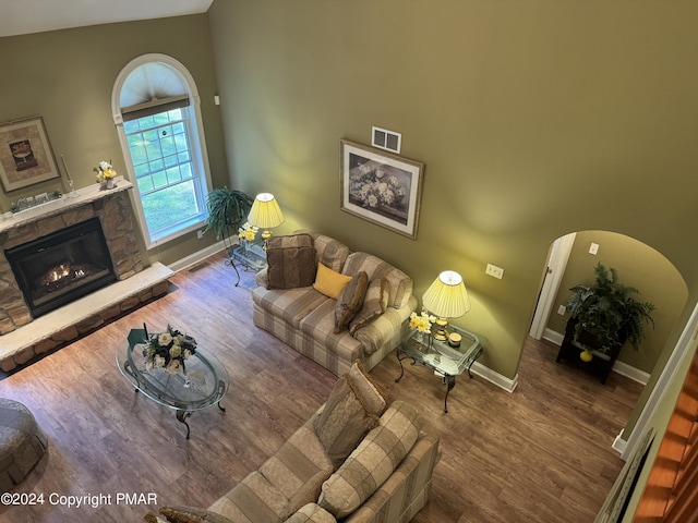 living area with visible vents, wood finished floors, arched walkways, a fireplace, and baseboards