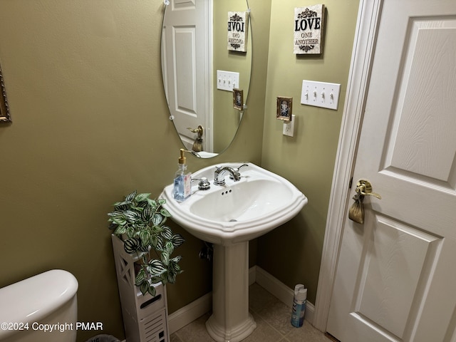 bathroom featuring tile patterned floors, toilet, baseboards, and a sink