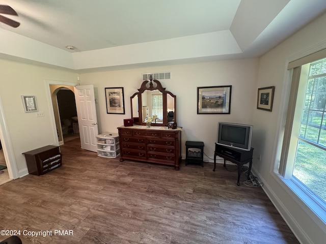 bedroom featuring a tray ceiling, visible vents, arched walkways, and dark wood finished floors