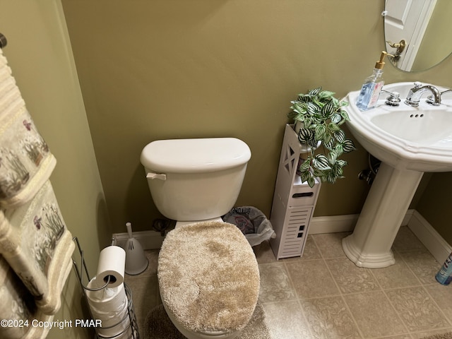 bathroom with ornate columns, tile patterned flooring, toilet, and baseboards