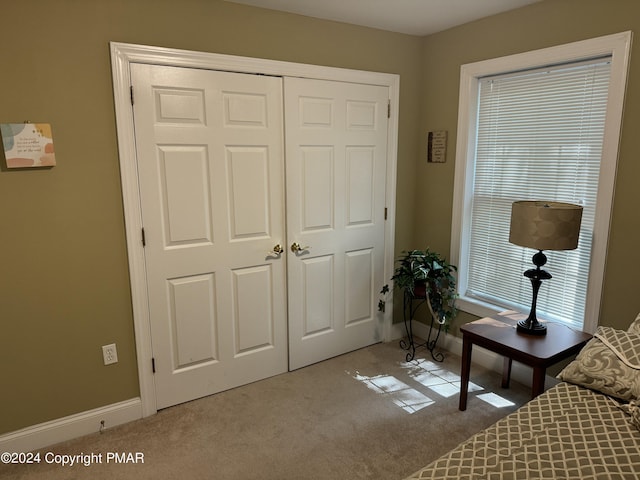 carpeted bedroom featuring a closet and baseboards