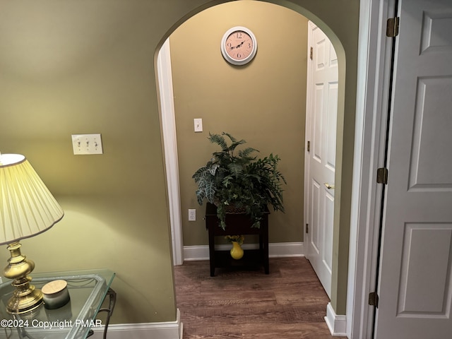 interior space with baseboards, arched walkways, and dark wood-style flooring