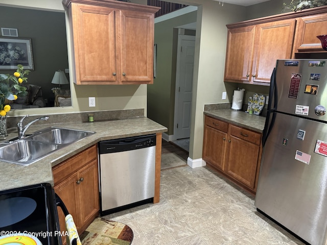 kitchen featuring visible vents, a sink, appliances with stainless steel finishes, brown cabinetry, and baseboards