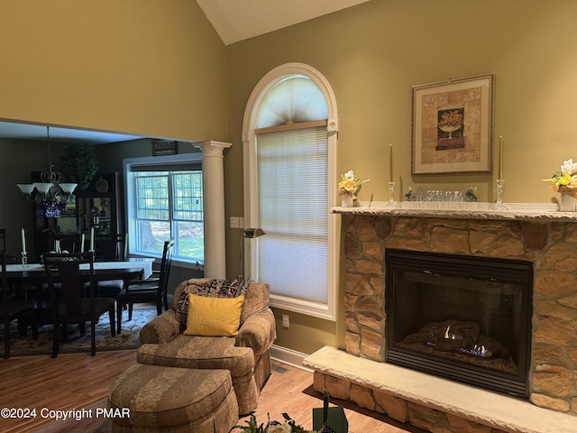 living room featuring a stone fireplace, wood finished floors, and vaulted ceiling