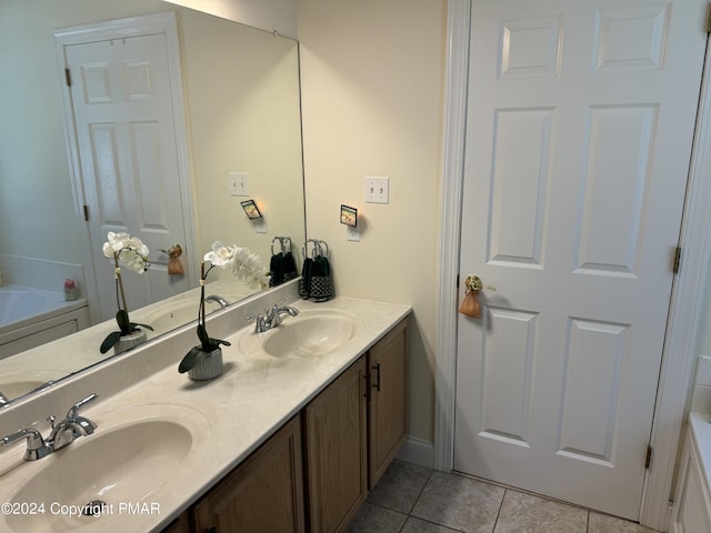 full bath with tile patterned flooring, double vanity, a bathtub, and a sink