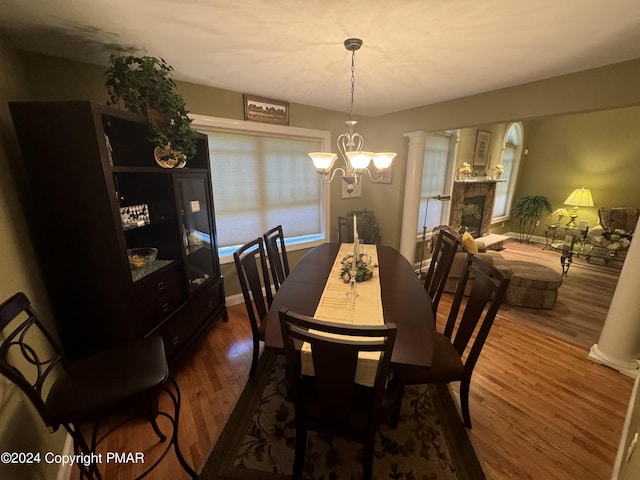 dining space with a chandelier, baseboards, ornate columns, and wood finished floors