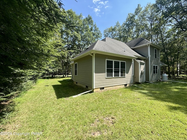 view of side of property featuring a yard, roof with shingles, and crawl space