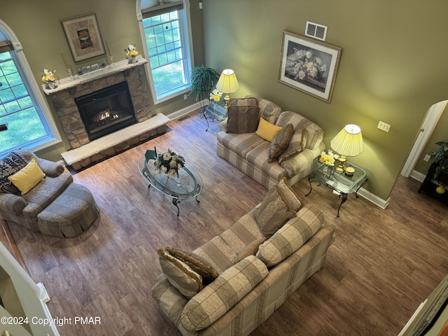 living room featuring wood finished floors, a fireplace, visible vents, and a healthy amount of sunlight