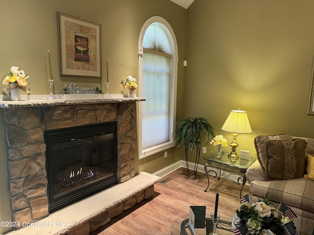 living area featuring baseboards, wood finished floors, and a fireplace