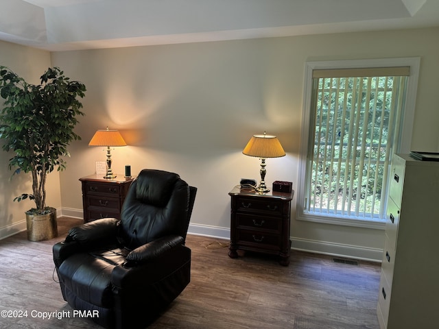 living area featuring visible vents, baseboards, and wood finished floors