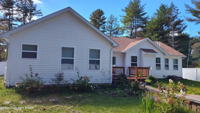 rear view of house with fence and a deck