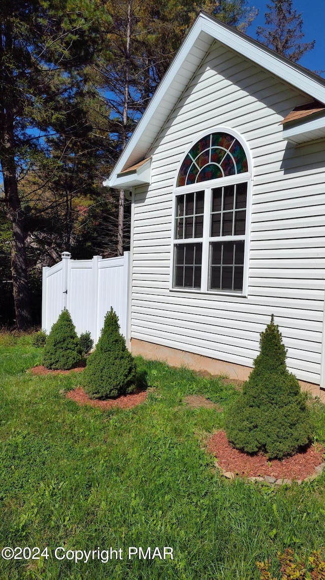 view of property exterior featuring fence and a lawn