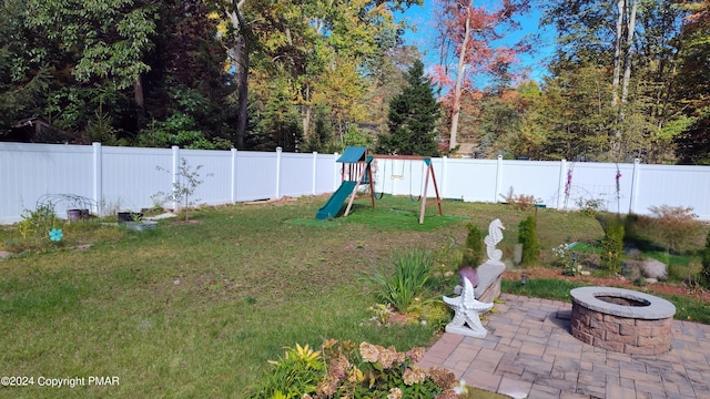 view of yard featuring an outdoor fire pit, a playground, and a fenced backyard