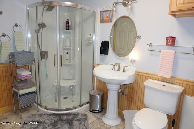 bathroom featuring a shower with door, toilet, tile patterned flooring, and wood walls